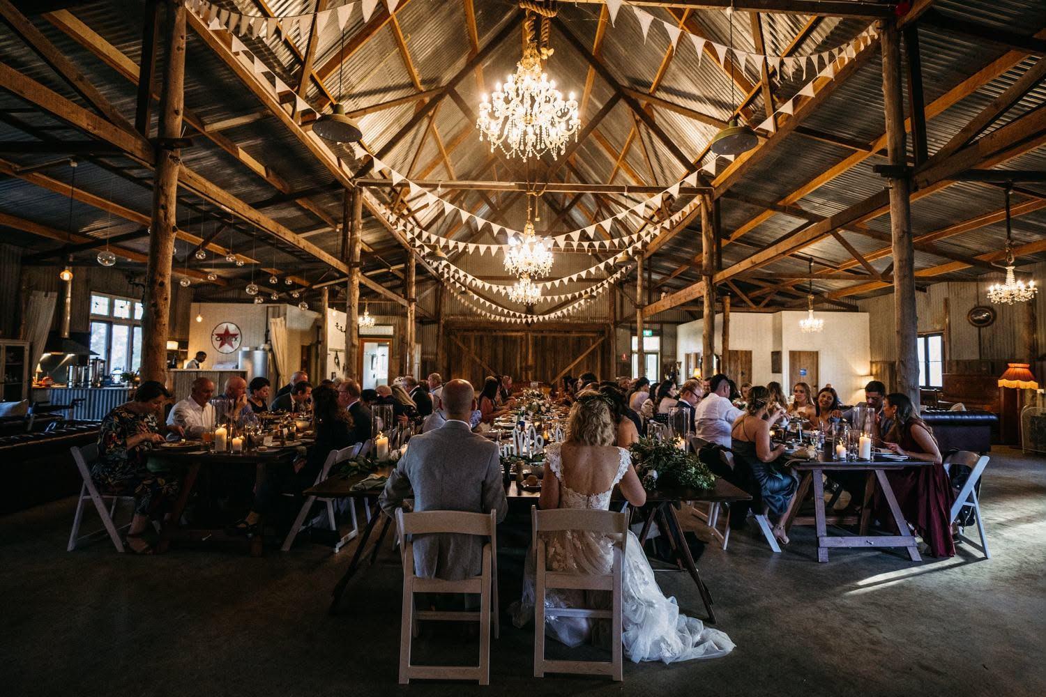 Wedding dinner under chandeliers inside the barn